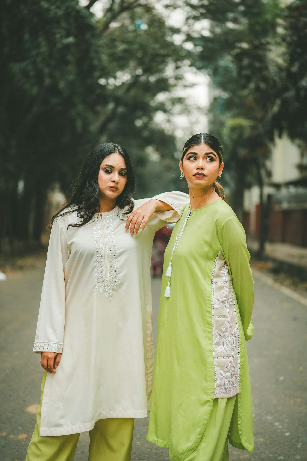 Two women pose in traditional, embroidered outfits.
